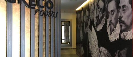 A hallway with a sign reading "CRECO rooms" and a large mural with faces.