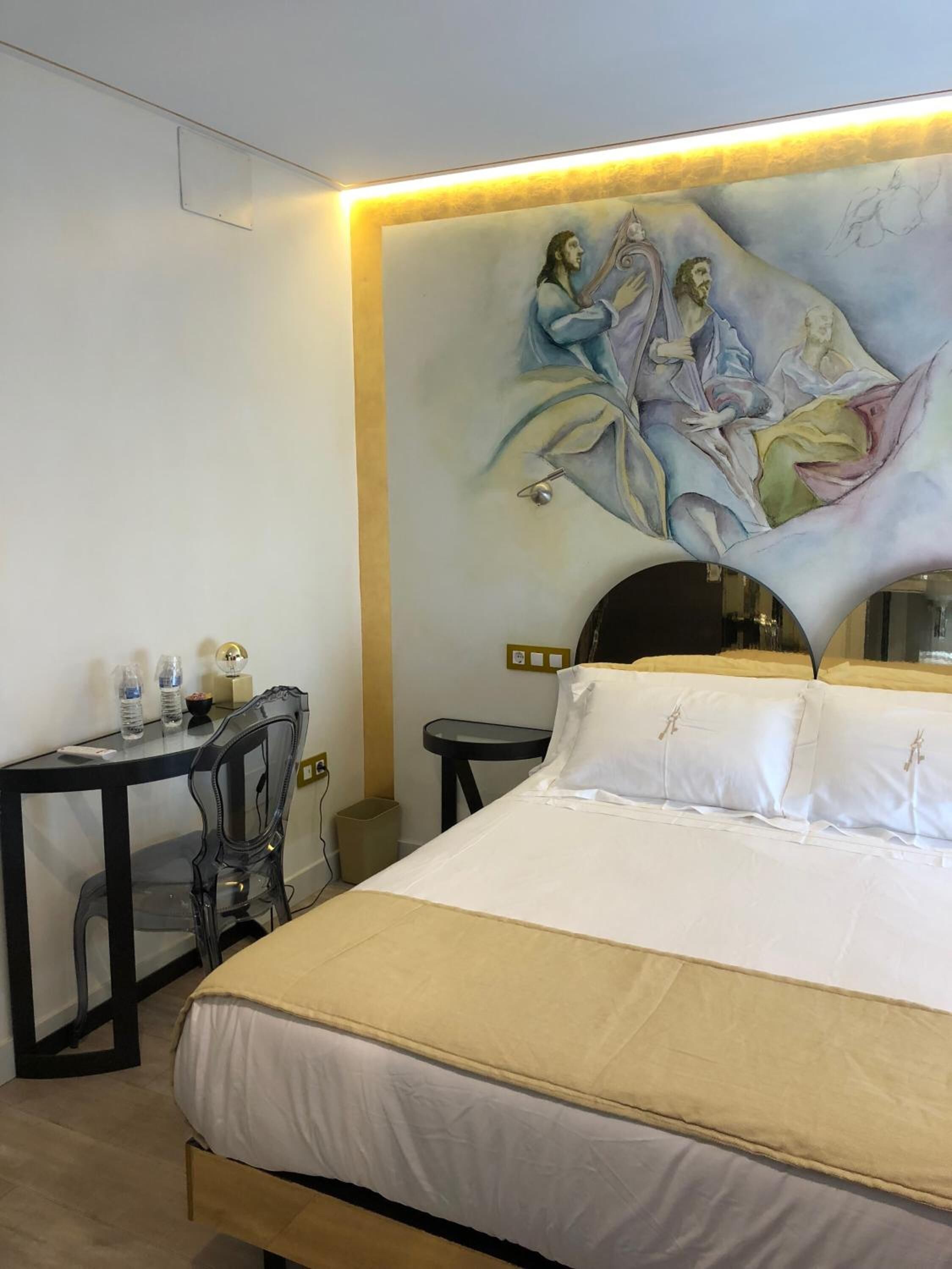 Una habitación de hotel con una cama, un escritorio, una silla y un mural en la pared.
