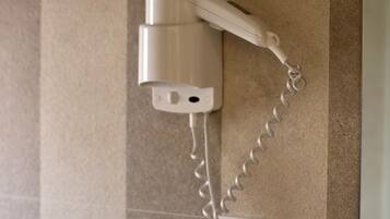 Un secador de pelo fijado a la pared, con un enchufe debajo.