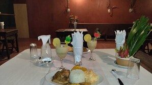 A dining table set with a plate of food, a glass of beverage, and a salt shaker.