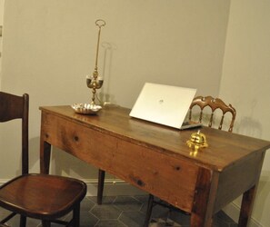 A wooden dining table with a laptop, a brass candlestick, and a small bowl. - Locanda San Tomaso (Pietra Ligure)