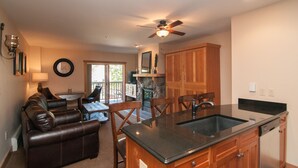 A compact kitchen with a central island, wooden cabinets, and a stone fireplace. - 1BR/2 FULL Baths +Murphy bed & Sleeper Sofa, Sleeps 6, to Gondola in 337 steps (Keystone)