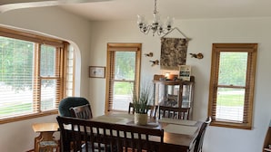 A dining area with a wooden table and chairs, a chandelier, and a 'Welcome to the River' sign above.