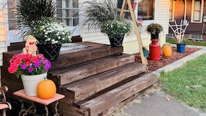 A house with a front porch, wooden steps, and various potted plants.