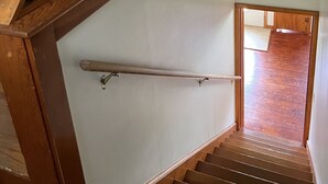 A wooden staircase with a handrail, leading to an open doorway.