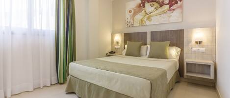 Quarto com cama, mesas de cabeceira, luminária na parede e um quadro.