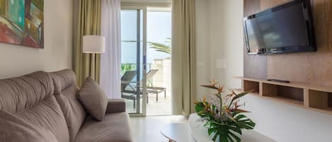 A modern living room with a sofa, a coffee table, a TV mounted on a wooden panel, and a balcony with a chair and table.