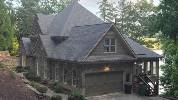 Une maison en pierre avec un toit en pente et un garage.