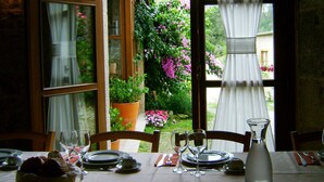 Mesa lista para comer con vista a un jardín a través de una ventana.
