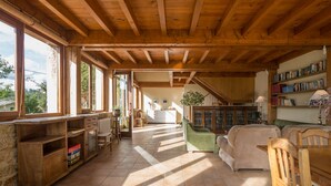 Un espacio habitable amplio con techo de madera, ventanas grandes, una escalera y una estantería.