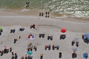 Une plage avec des gens, des parasols et des chaises de plage.