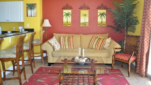 A living room with a sofa, chairs, a coffee table, and a dining area with chairs and a table.
