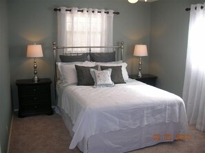 Cozy retreat with a single bed, bedside tables, and sheer curtains.