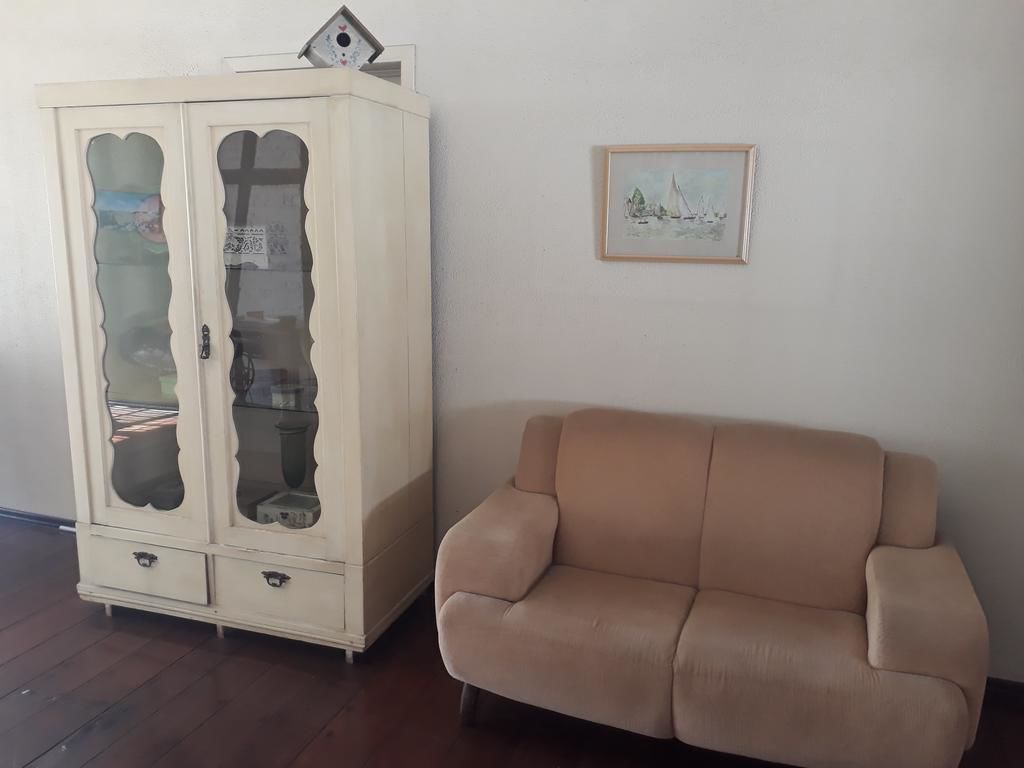 Una habitación con un sofá color beige y un mueble blanco con puertas de cristal.