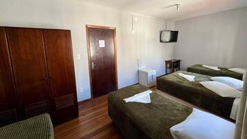 Habitación de hotel con dos camas, un armario, un televisor y una mesita.