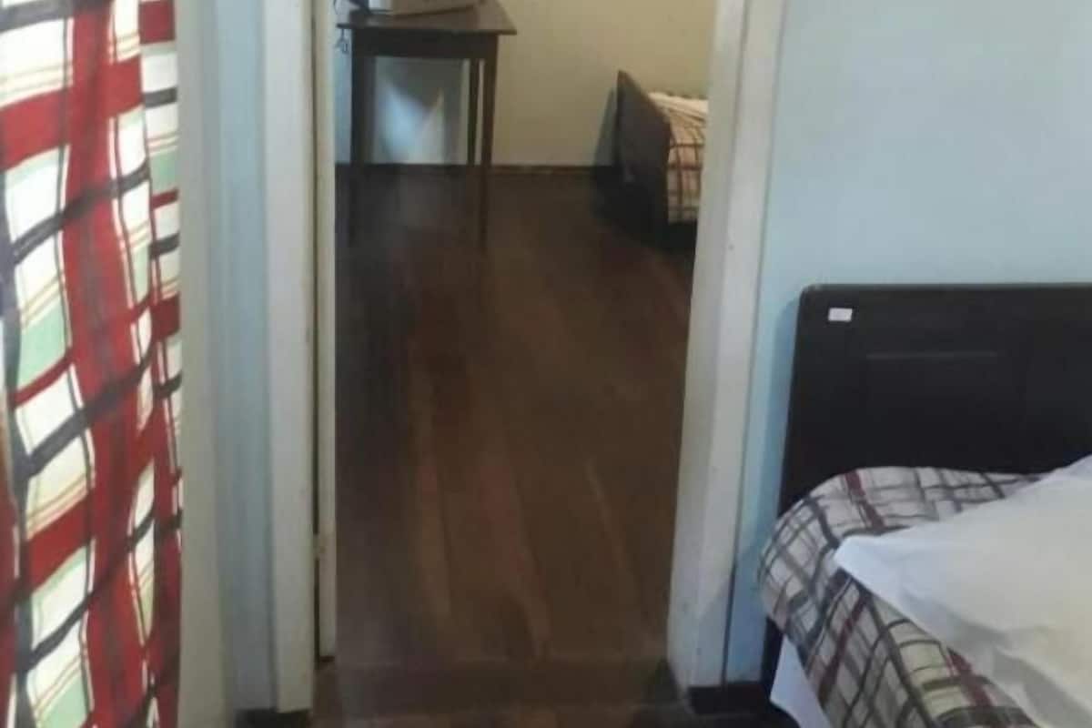 A narrow hallway leading to a bedroom with a bed and a television on a small table.