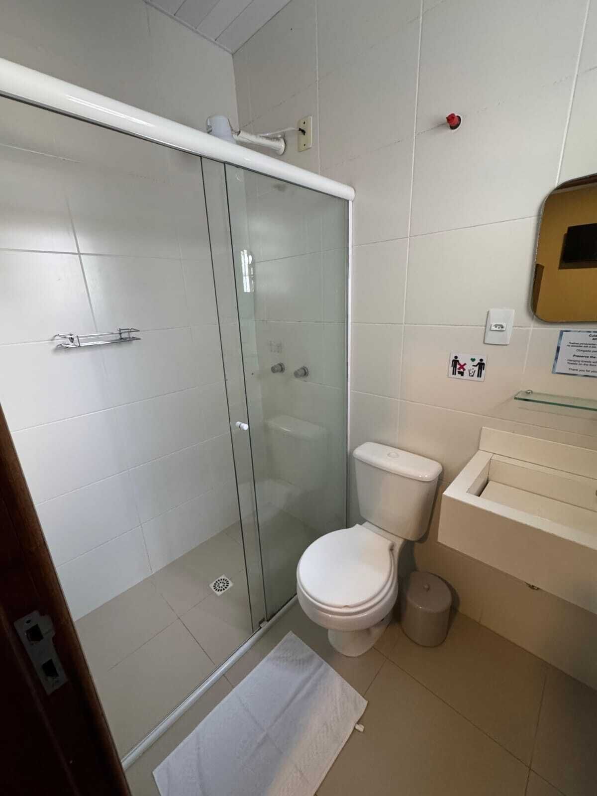 Un baño pequeño con cabina de ducha de vidrio, inodoro y lavamanos.
