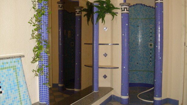 A bathroom with blue-tiled walls, a checkered floor, and a plant on the left. - Hotel Waldschlösschen (Werra-Suhl-Tal)