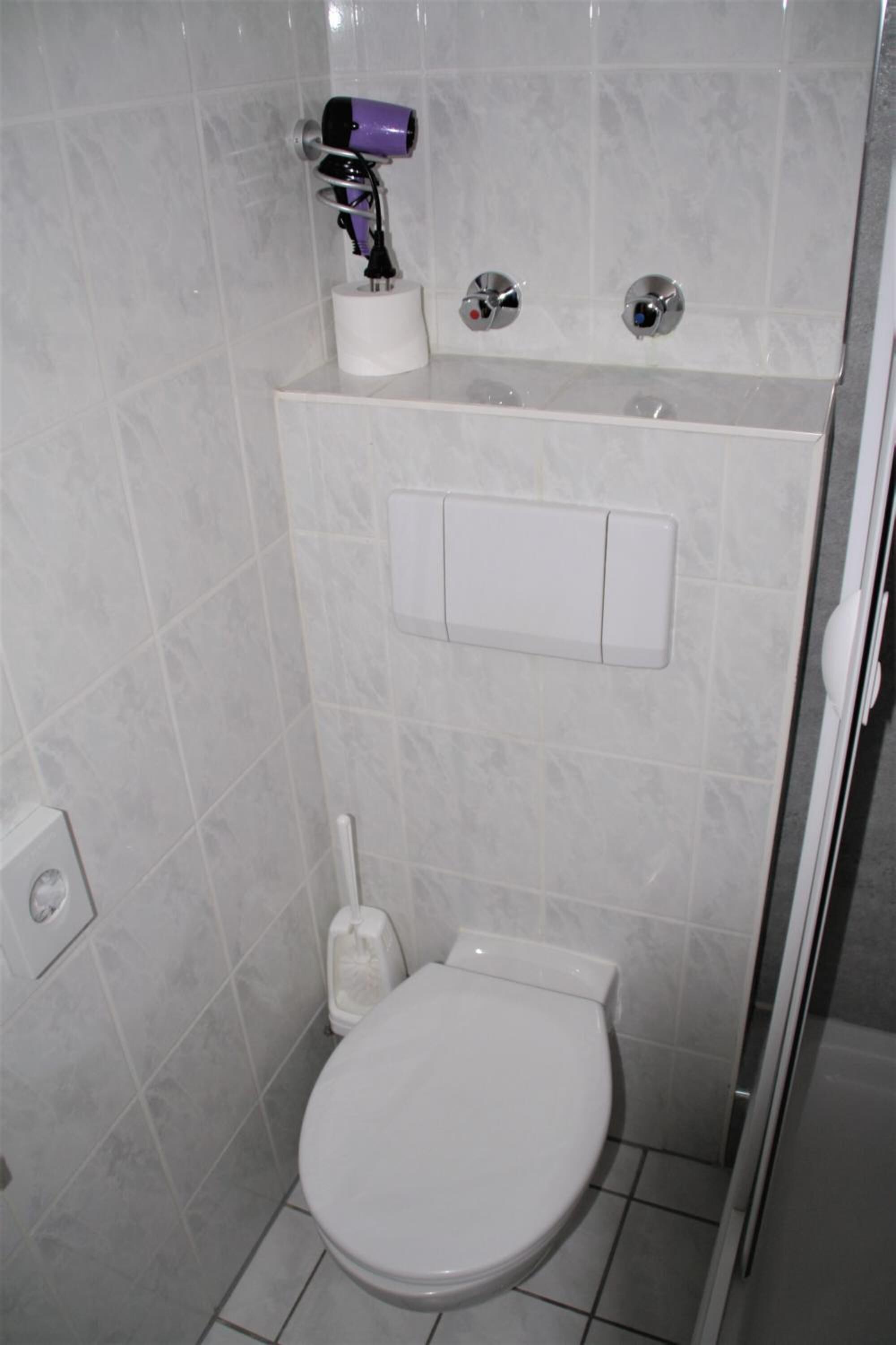 A small bathroom with a toilet, a hand dryer, and a sink.