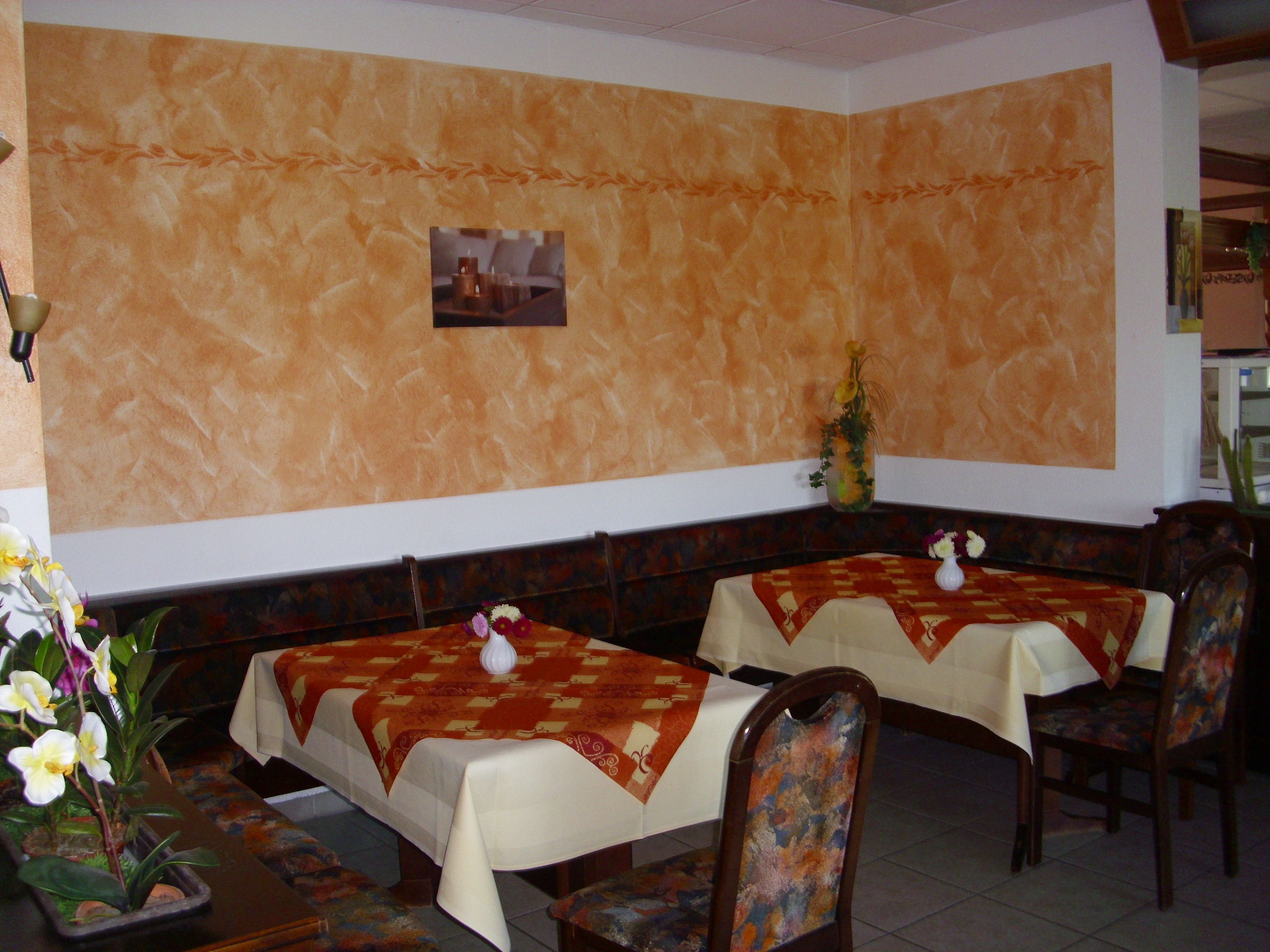 Un restaurante con dos mesas dispuestas para comer, sillas y una planta decorativa.