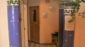 A hallway with checkered floor tiles, a wooden door, and blue-tiled walls. - Hotel Waldschlösschen (Werra-Suhl-Tal)