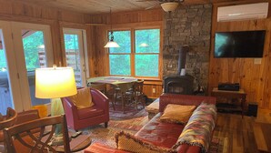 A cozy cabin interior with a fireplace, a television, a dining area, and a leather sofa.