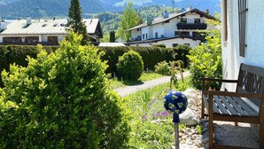 A mountain view with a building, a bench, and a garden.