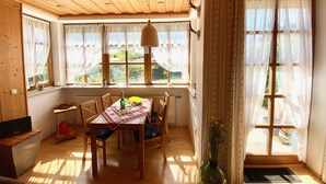 A dining area with a wooden table, chairs, and a vase of flowers.
