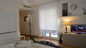 Ein modernes Wohnzimmer mit Essbereich, Fernseher und großem Fenster.