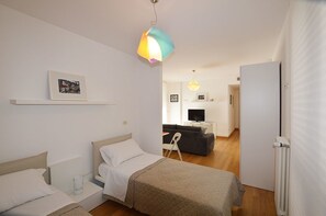 Una habitació d'hotel moderna amb un llit, una taula de nit i una televisió al fons.