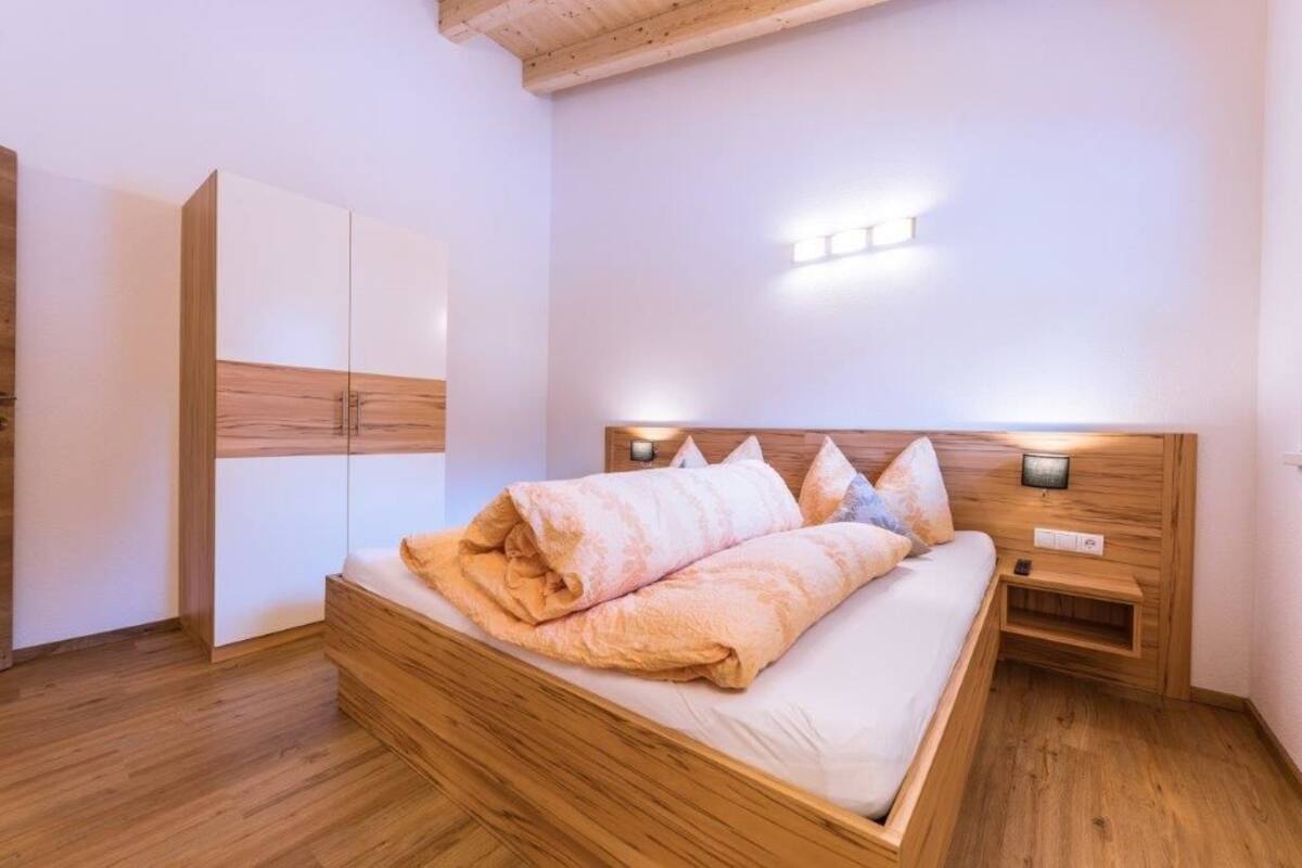 A bedroom with a wooden bed frame, a nightstand, and a wardrobe.