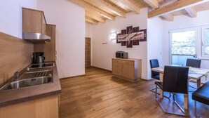Et moderne køkken med træbjælker, et indbygget komfur og en spiseplads med bord og stole.