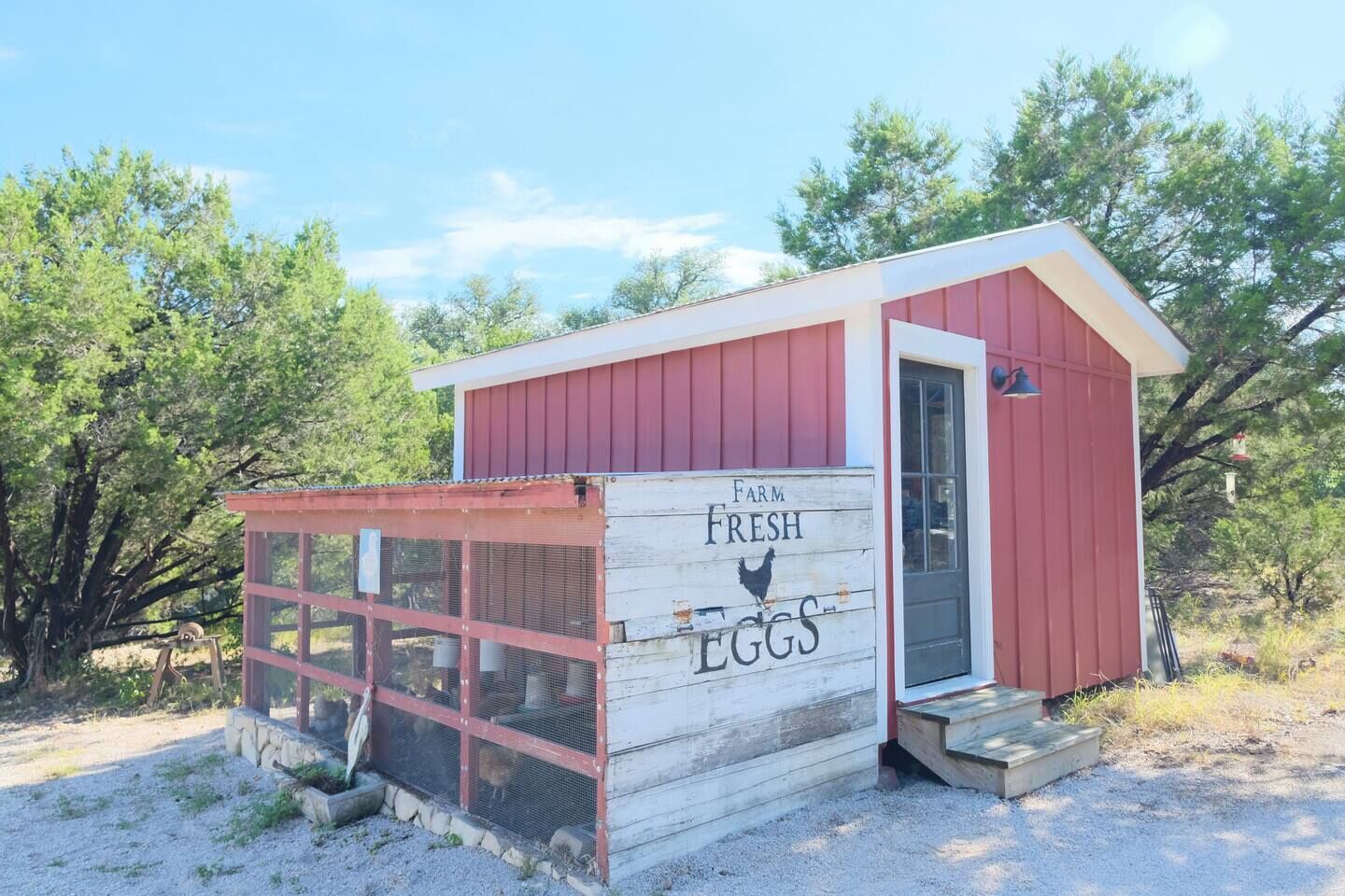A small, single-story building with a red exterior and a white door, labeled "Farm Fresh Eggs."