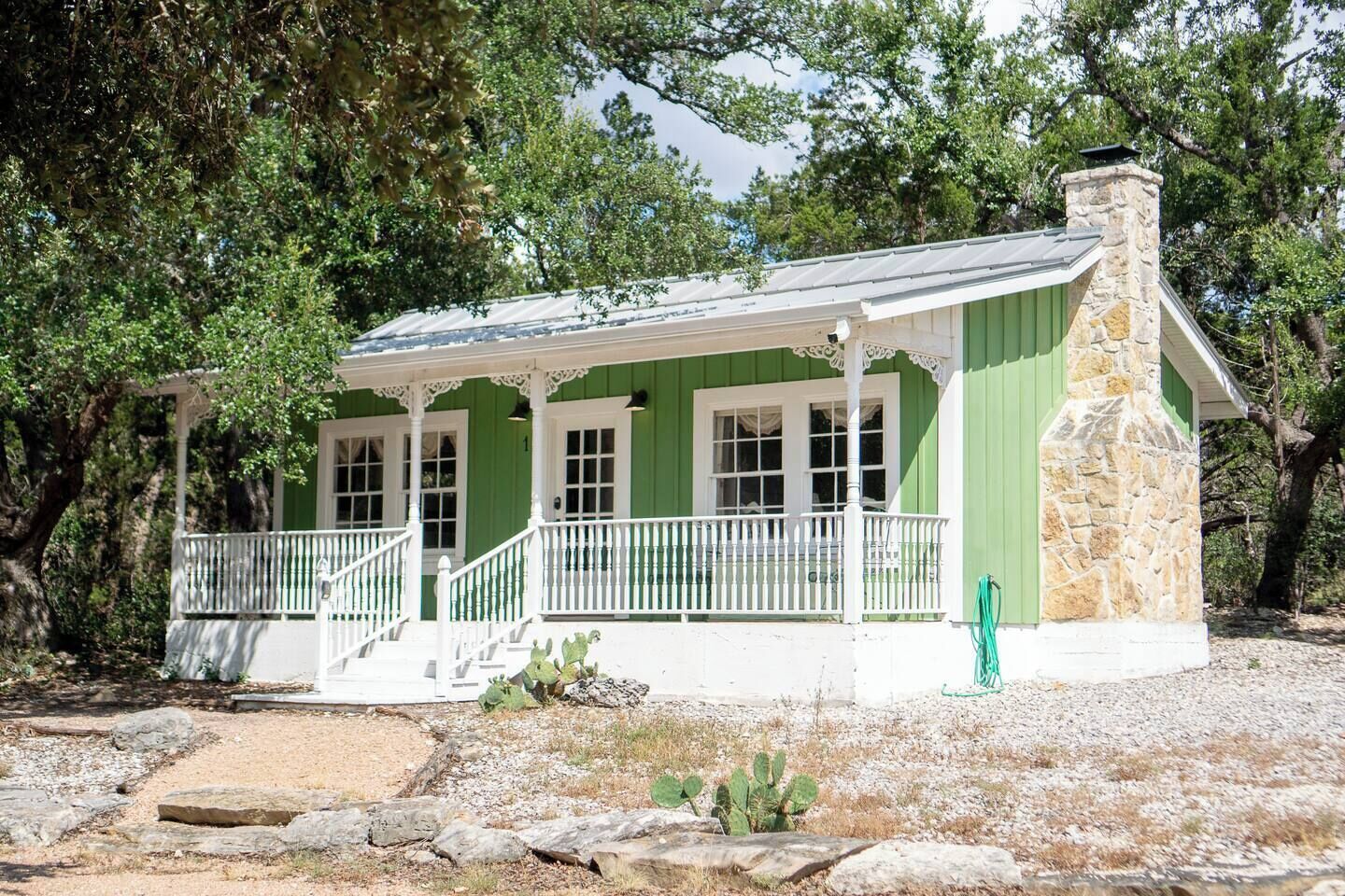 Un bâtiment écologique avec une cheminée en pierre, un porche blanc et de nombreuses fenêtres.