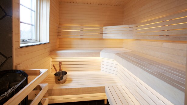 A sauna with wooden benches and a stone wall. - Fjällfrid Stugor (Bruksvallarna)