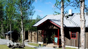A rustic cabin with a metal roof, wooden walls, and a porch. - Fjällfrid Stugor (Bruksvallarna)