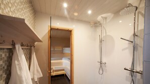 A modern bathroom with a shower, a wooden bench, and a visible doorway leading to another room. - Fjällfrid Stugor (Bruksvallarna)