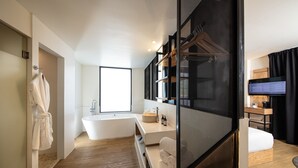 A modern bathroom with a freestanding bathtub, a large mirror, and a wooden floor. - Auténtico Monterrey (San Pedro Garza García)