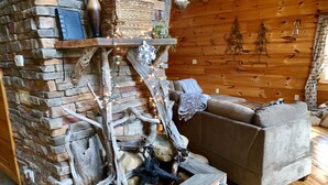 A cozy room with a stone fireplace, wooden logs, and a brown sofa. - Luxury Lake Chalet Hot Tub Private Boat Slip  Amazing Mountain View’s Sleeps 10 (Butler)