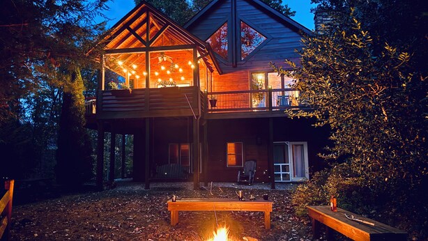 A two-story wooden cabin with a balcony, a fire pit, and outdoor seating. - Luxury Lake Chalet Hot Tub Private Boat Slip  Amazing Mountain View’s Sleeps 10 (Butler)