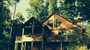 A two-story wooden cabin with a balcony, surrounded by trees. - Luxury Lake Chalet Hot Tub Private Boat Slip  Amazing Mountain View’s Sleeps 10 (Butler)