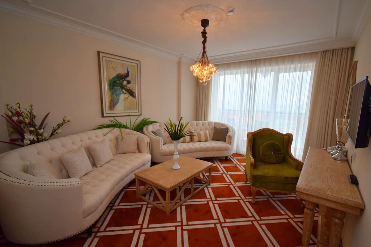 A living room with a beige sofa, a green armchair, a wooden coffee table, and a chandelier.