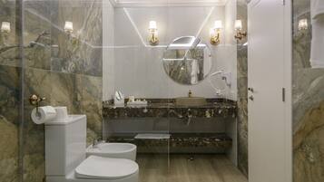 A modern bathroom with a marble wall, a round mirror, a sink, and a toilet.