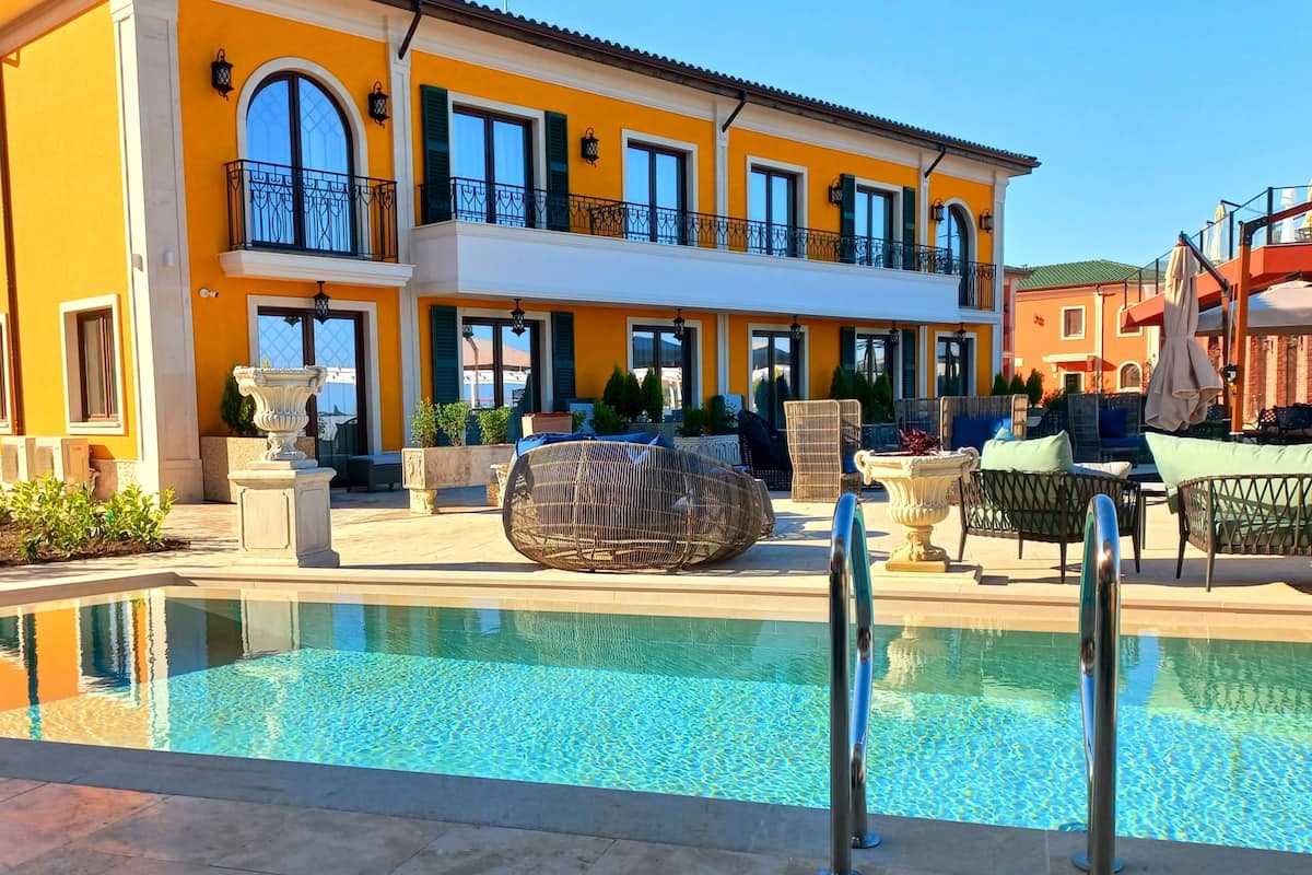 A two-story building with a pool, outdoor seating, and a balcony.