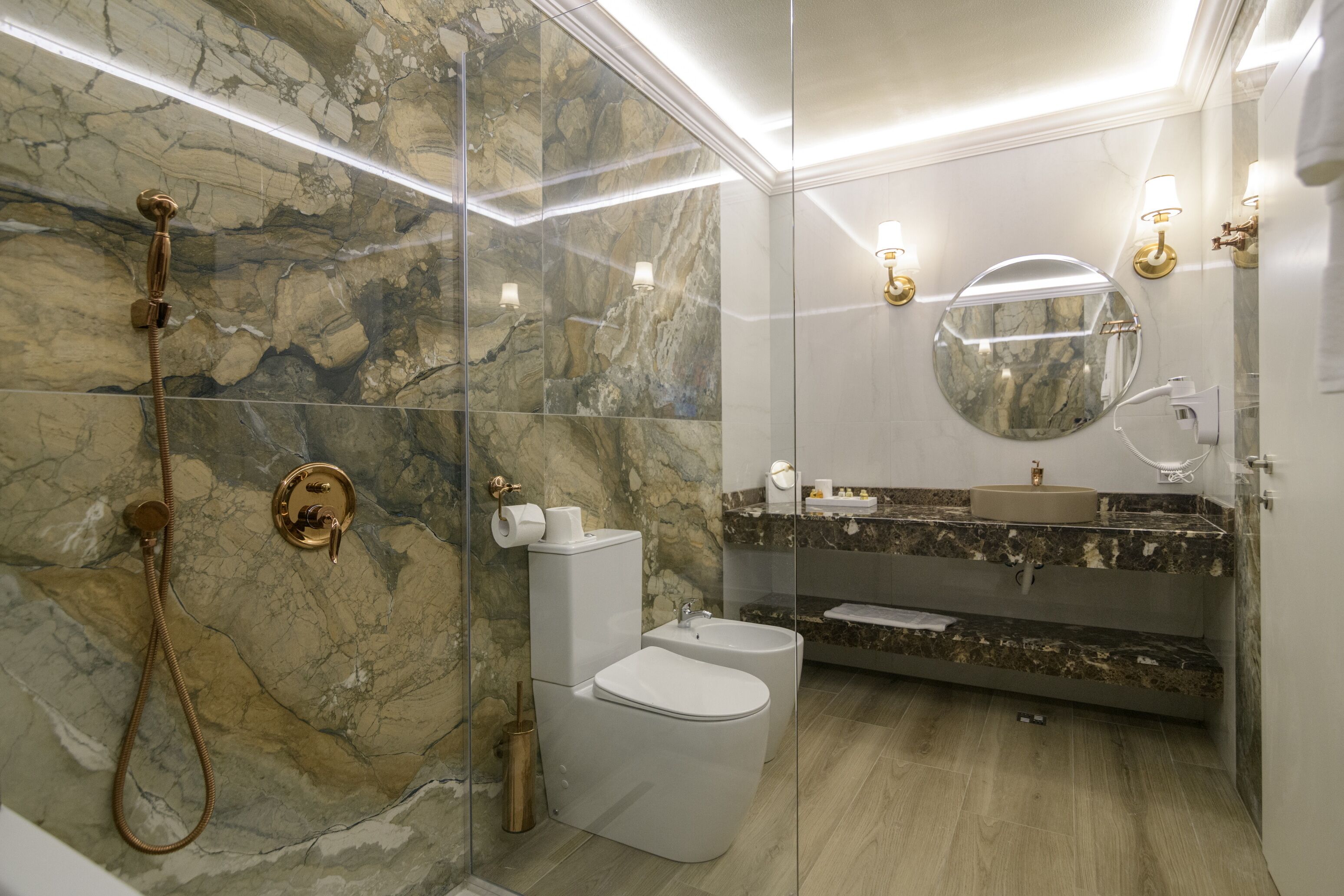 Un baño moderno con ducha envuelta en vidrio, inodoro y tocador con lavabo y espejo.