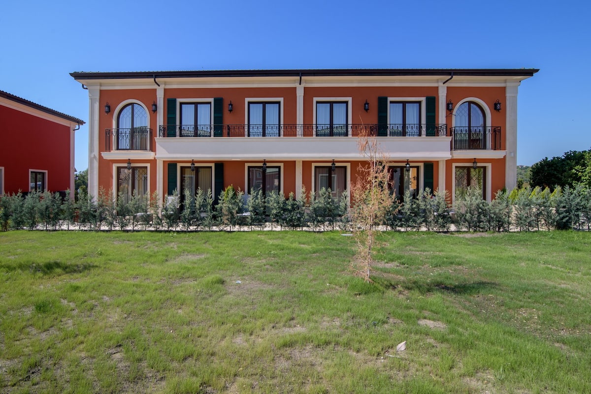 A multi-story building with a flat roof, large windows, and a balcony on the second floor.