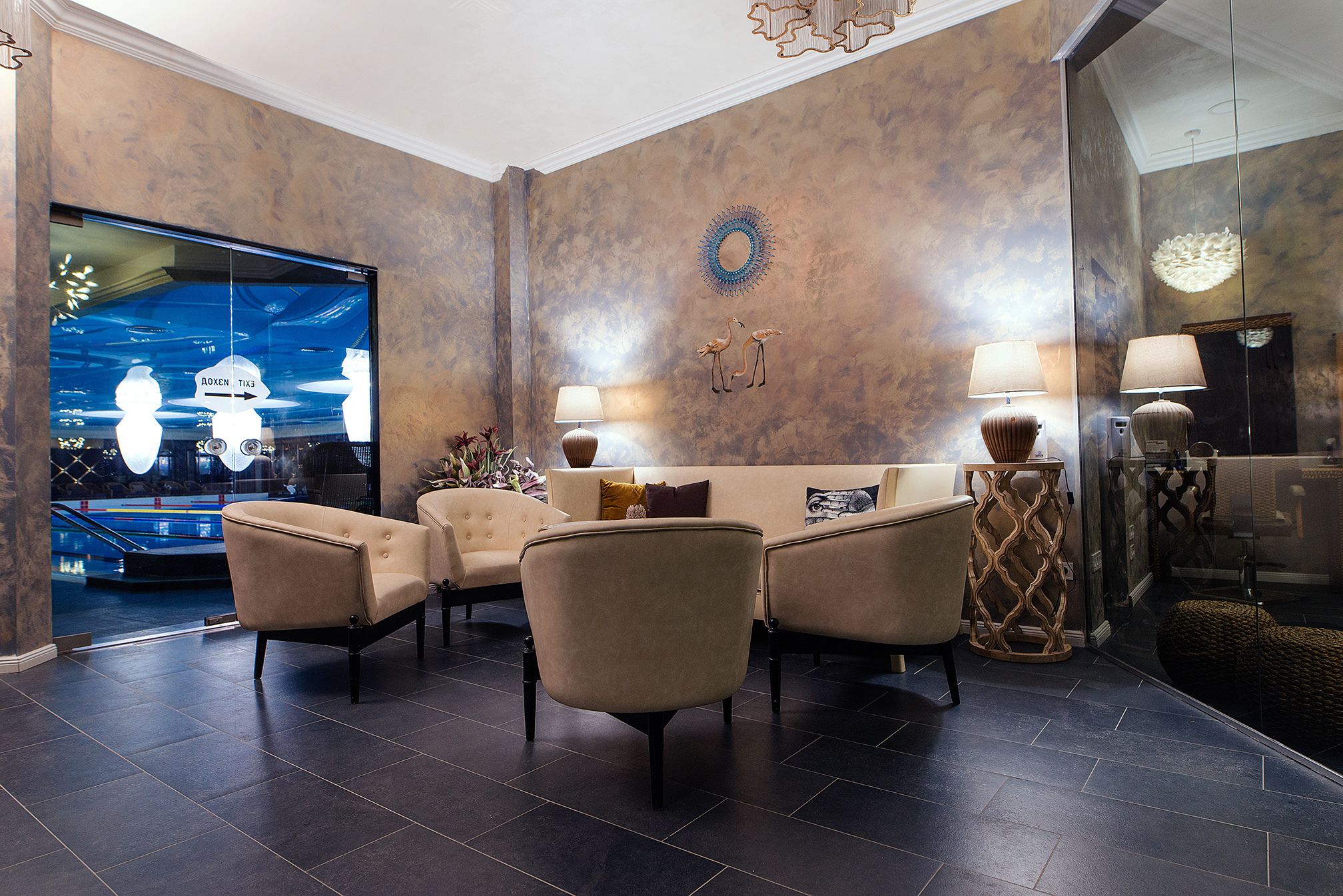 A lobby with a sofa set, two lamps, and a decorative mirror.