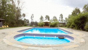 A rectangular swimming pool with a tiled edge, surrounded by a stone deck.