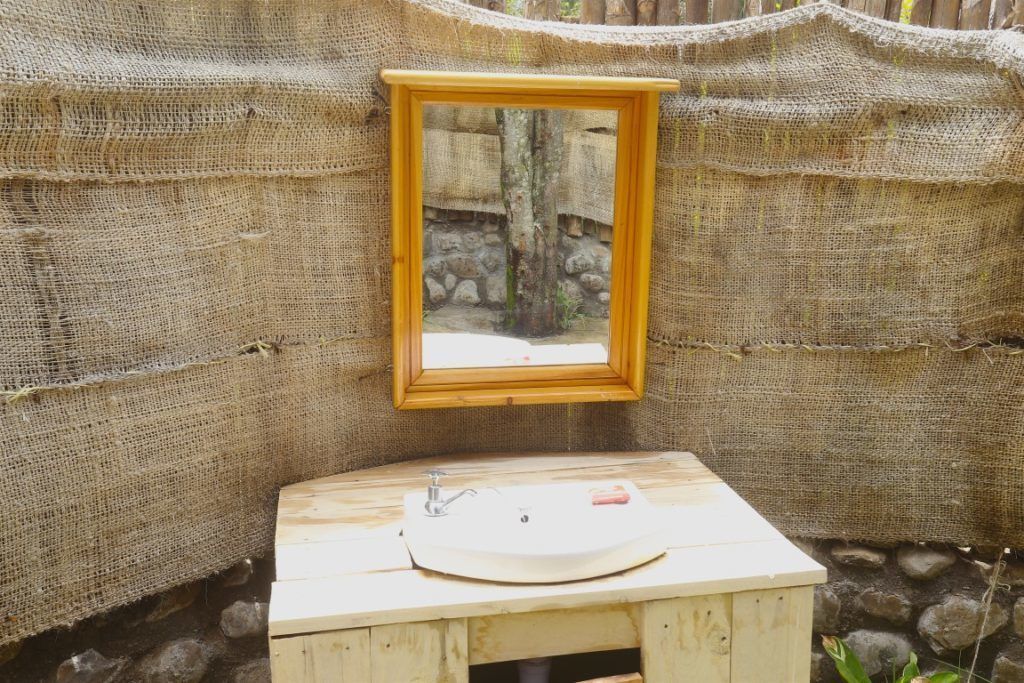 Un baño rústico con un lavamanos de madera y un espejo enmarco.