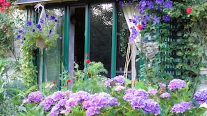 A garden with purple hydrangeas and hanging flower baskets. - Le Frêne Fringant (Sainte-Opportune-la-Mare)